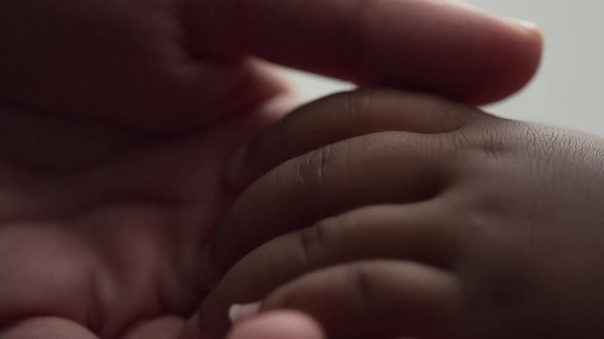 A woman caresses her toddlers fingers