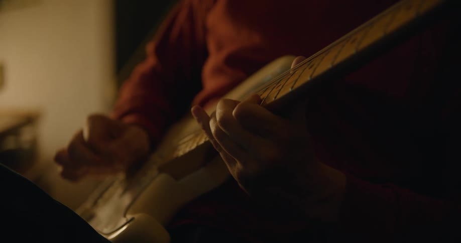 A man sitting in a chair wearing headphones and playing guitar