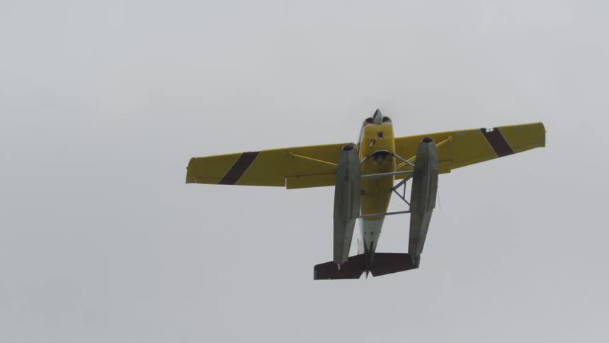 A seaplane flies overhead in a cloudy sky