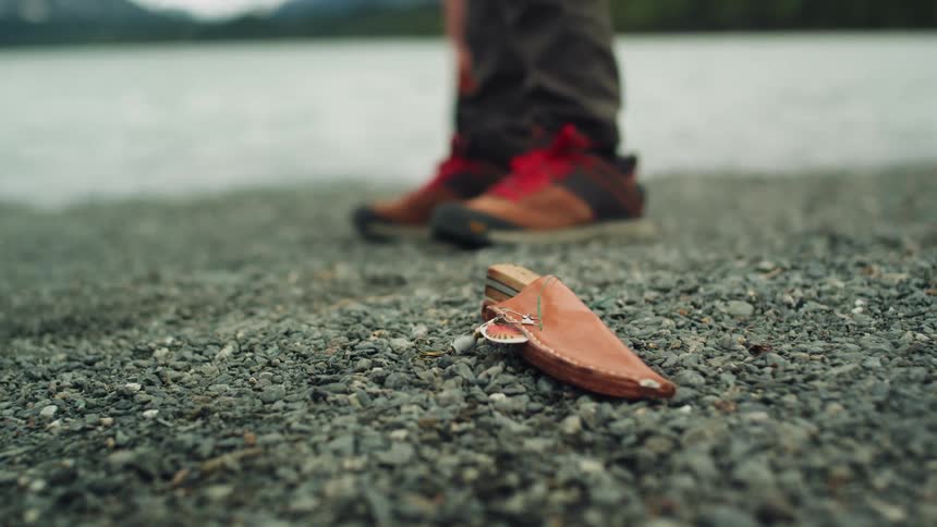 A person is standing next to a holstered knife on the ground