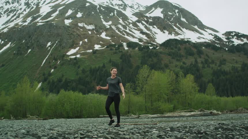 A woman throws a large branch on the ground and checks her watch