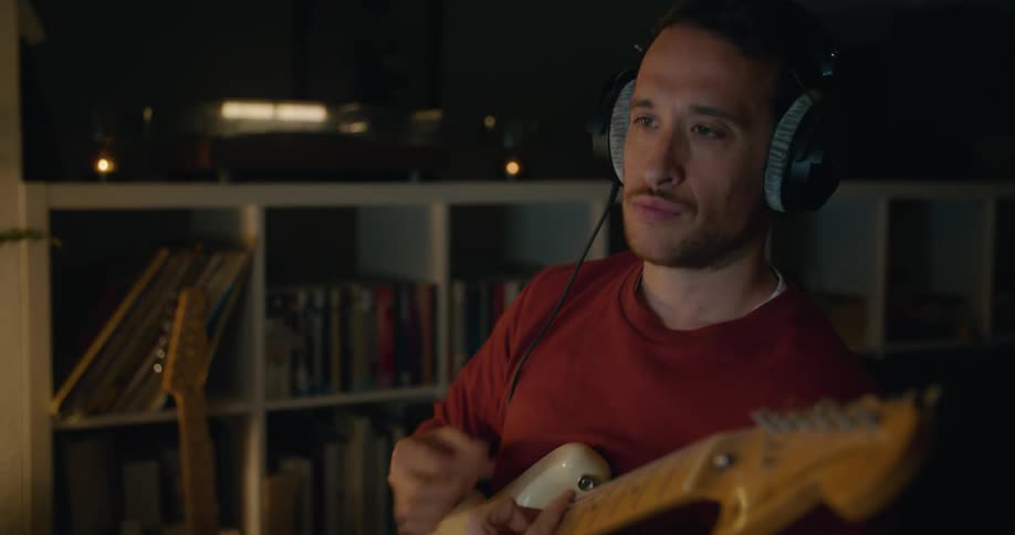 A man pushes buttons on his computer keyboard and then plays the guitar