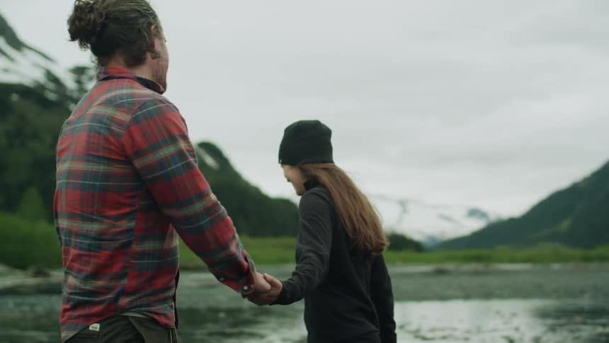 A couple hold hands while walking past the mountain