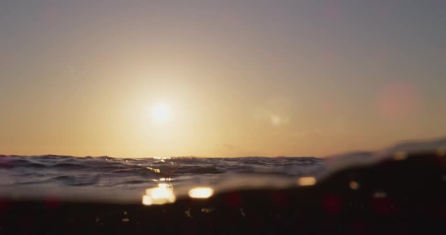 A golden sun and sky shine on the rolling ocean surface
