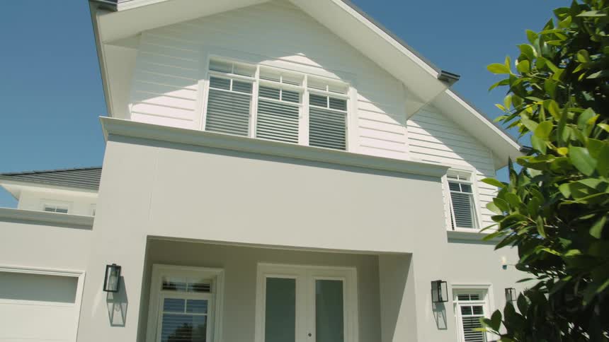 A residential home with two stories and a fresh paint job is past a leafy tree