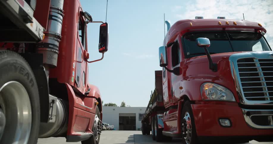 Two large red freight trucks are parked in the lot