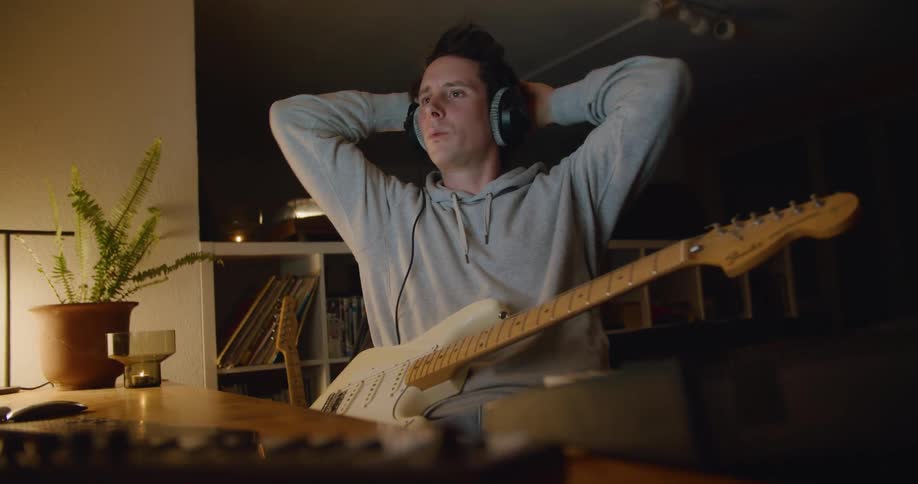 A man plays the guitar before listening back