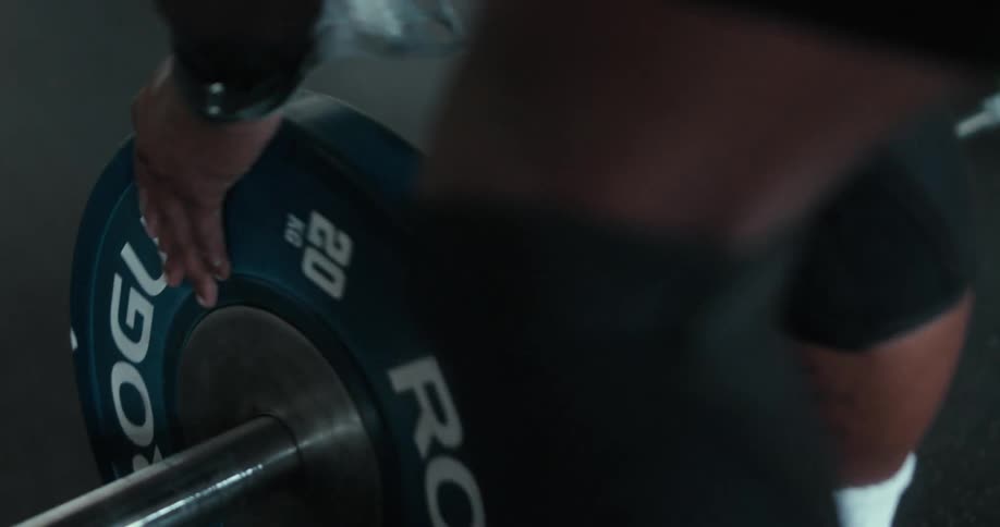 A muscled man adds weight to a dumbell