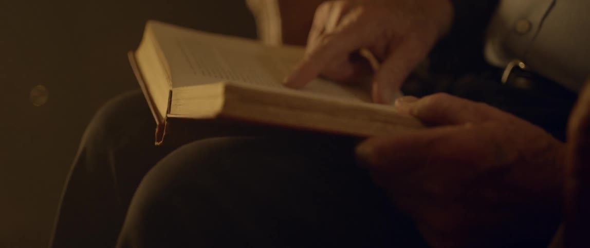 A person uses finger to trace text lines in a book