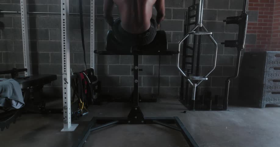 Bare chested man exercises on exercise machine