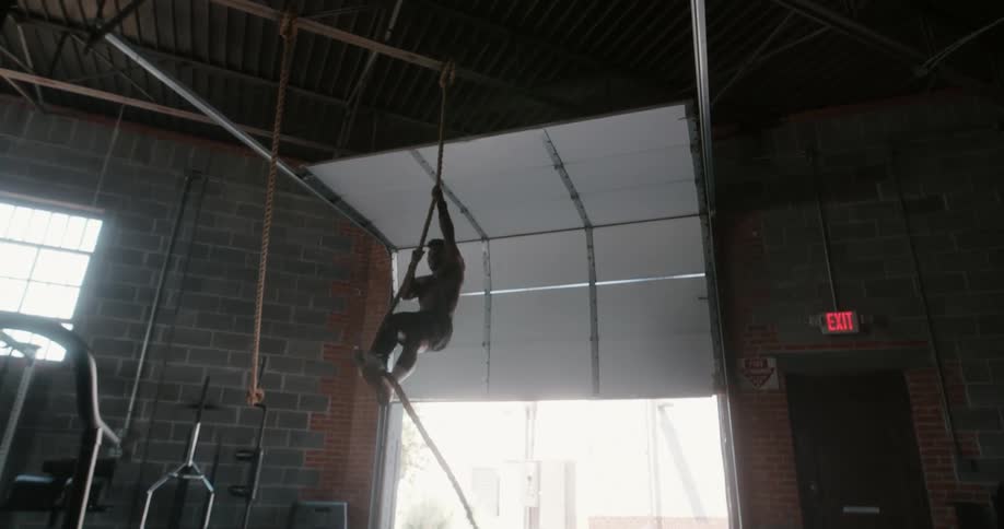 A muscular young athlete is exercising in a garage gym during the daytime