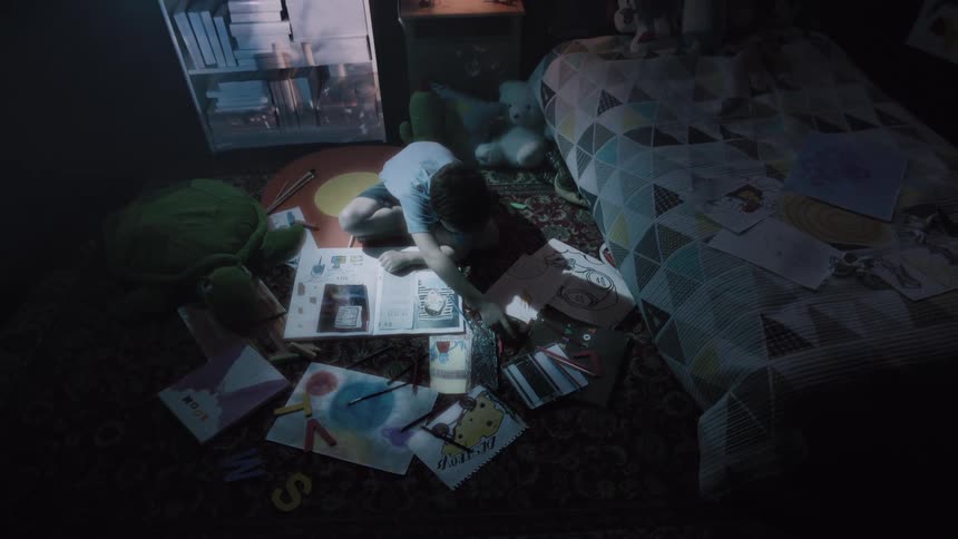 A child drawing while laying on the floor