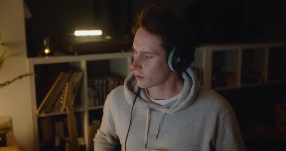 A man plays guitar while sitting at his computer