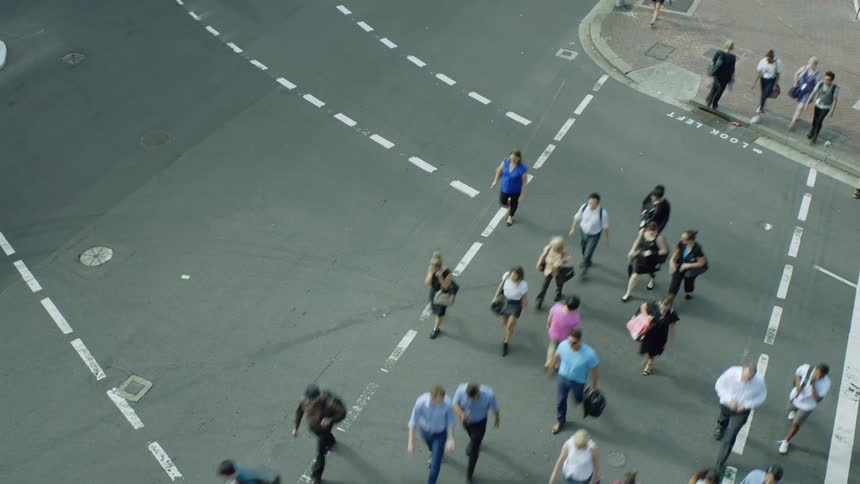Pedestrians cross street at intersection as vehicles including city bus also cross