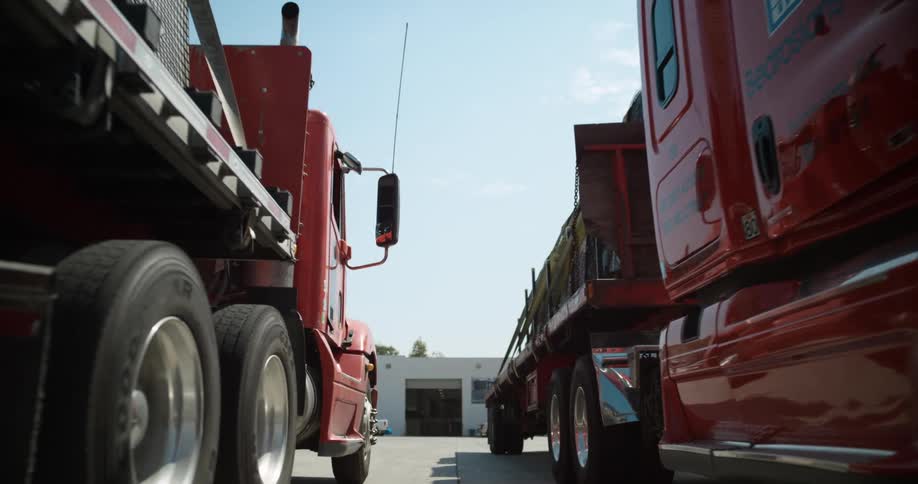 Two loaded trucks pass each other in a lot as one leaves and one arrives
