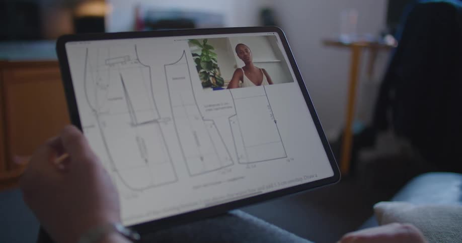 A person in a room using a stylus and tablet with a wall in the background
