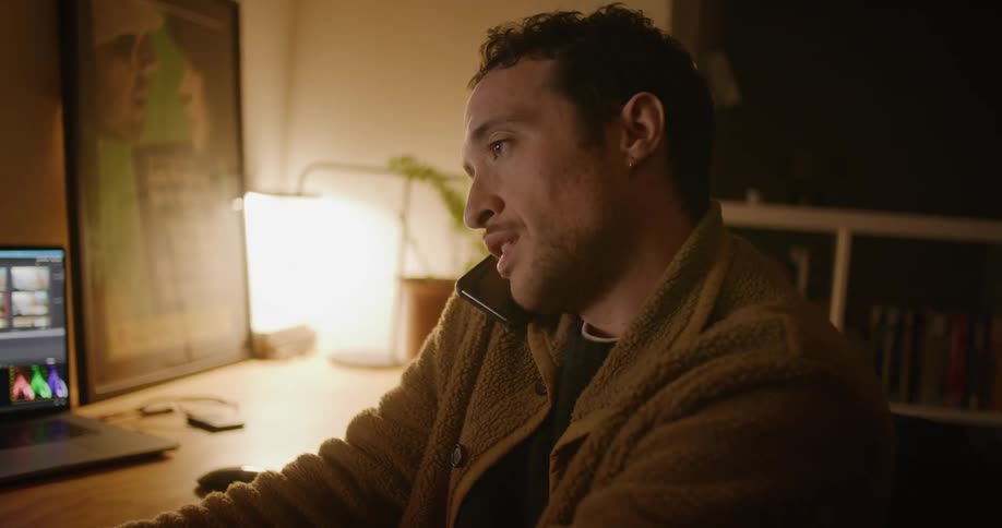 A man talking on a phone while using a laptop