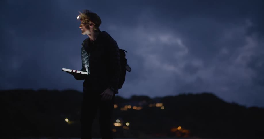A man is searching for something in the dark at sunset