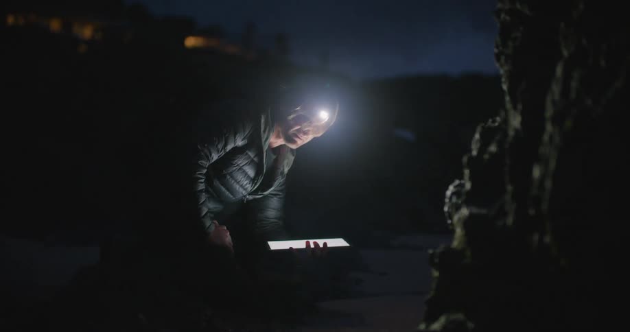 A man looking on a tablet at night