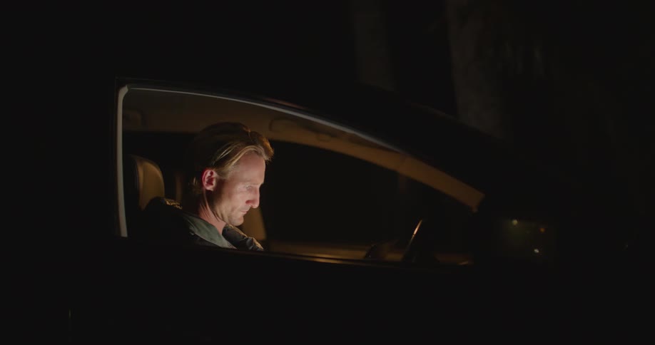 A man using a tablet in a car at night
