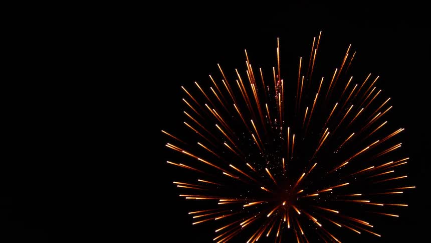 A red streak rises through the air and explodes in a fireworks display