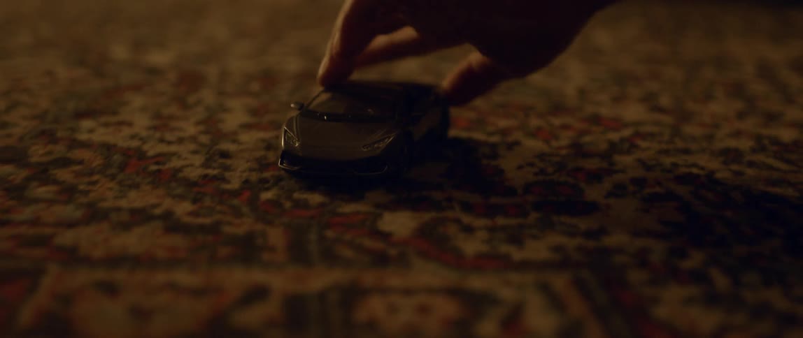 A boy pushes a car on a carpet