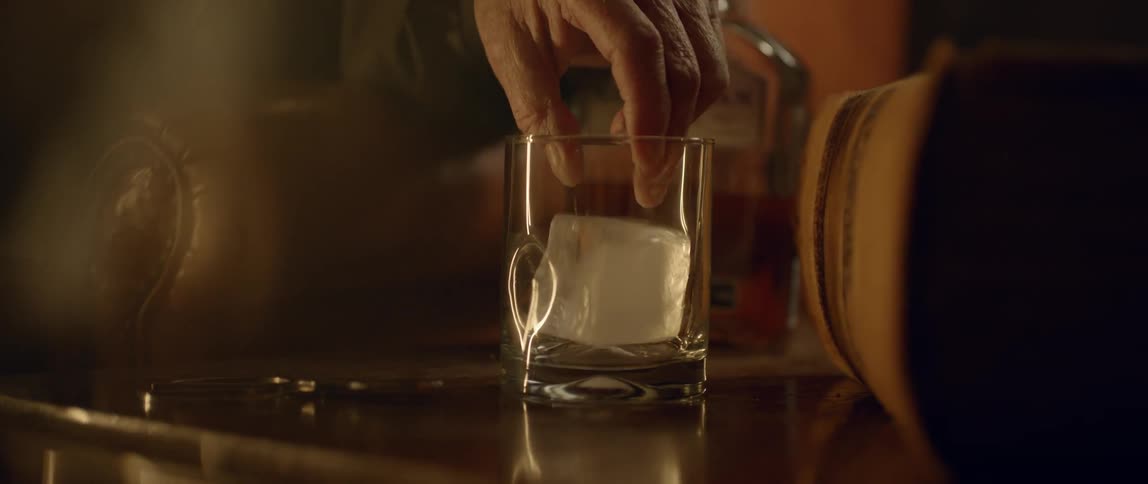 A large ice cube is dropped in a glass