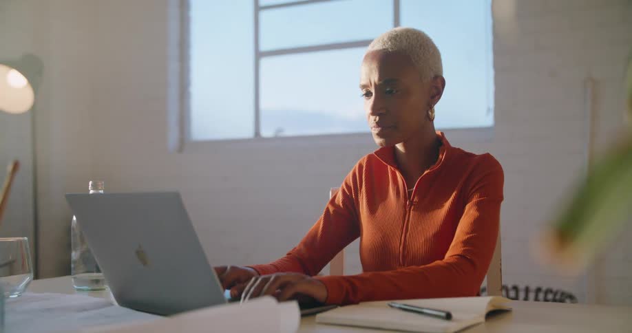 A woman types on her laptop in a spacious office