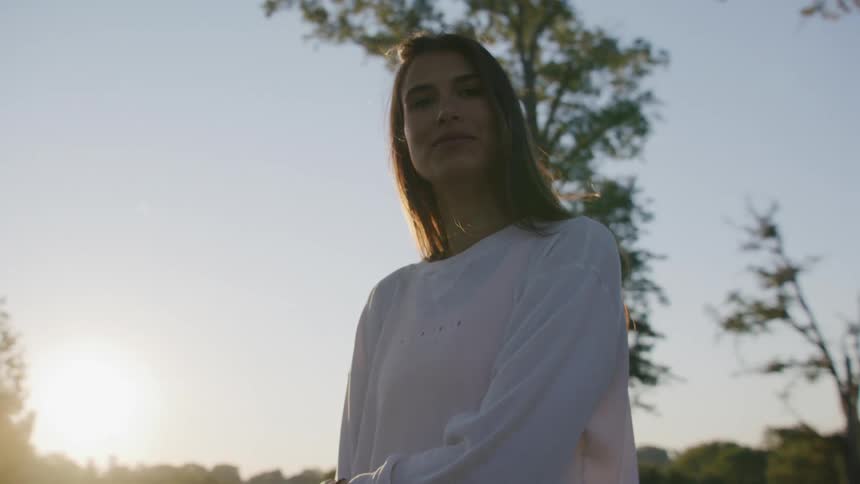 A woman smiles as she stands outside on a clear day