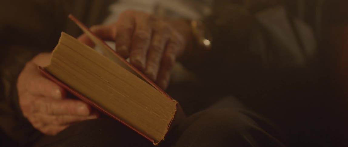 An elderly man closes a book
