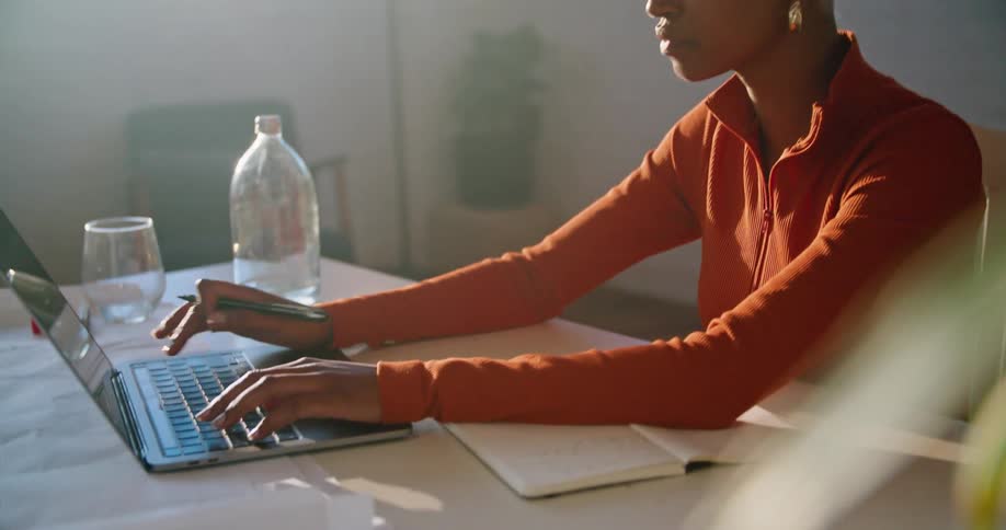 Woman sitting at the desk working on a laptop in the office at morning
