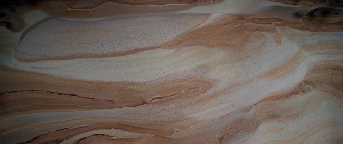 A rock formation in a canyon is made of swirls of white and brown sediment