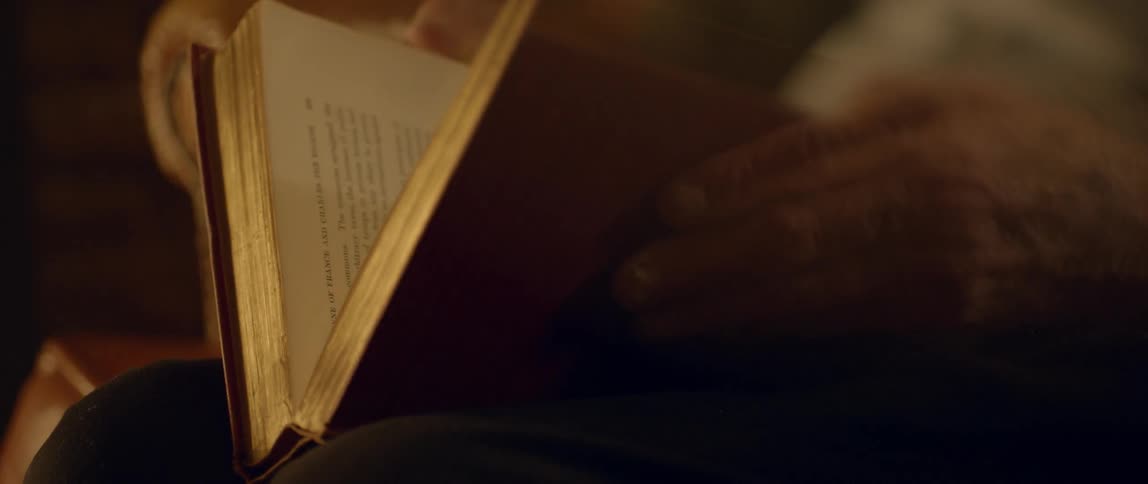 An elderly man closes a book