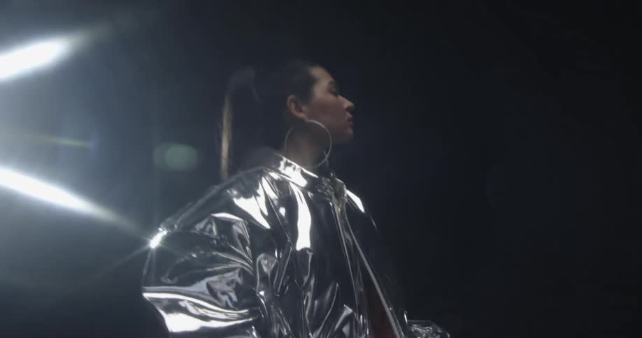 A model is standing on a stage under a spotlight