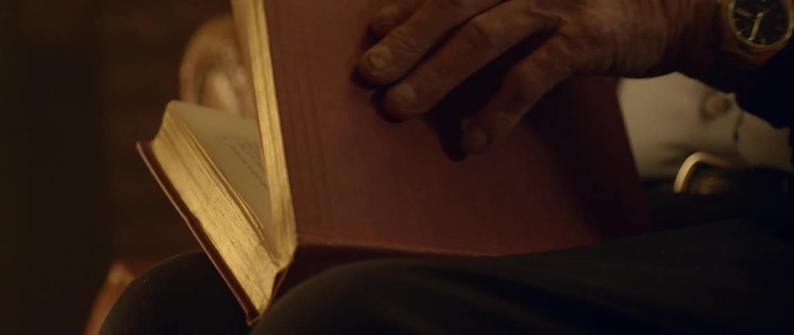 A person wearing a watch closes a book