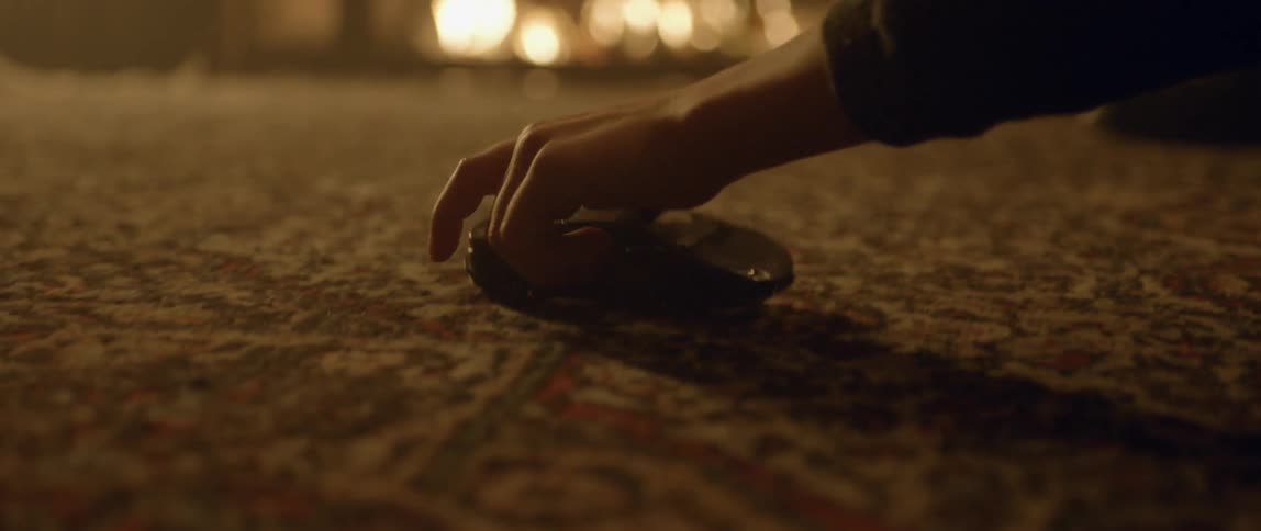 A hand is moving a toy car around a carpet by a fire