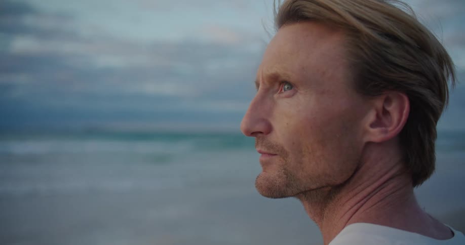 A man gazes at the ocean while standing on the beach