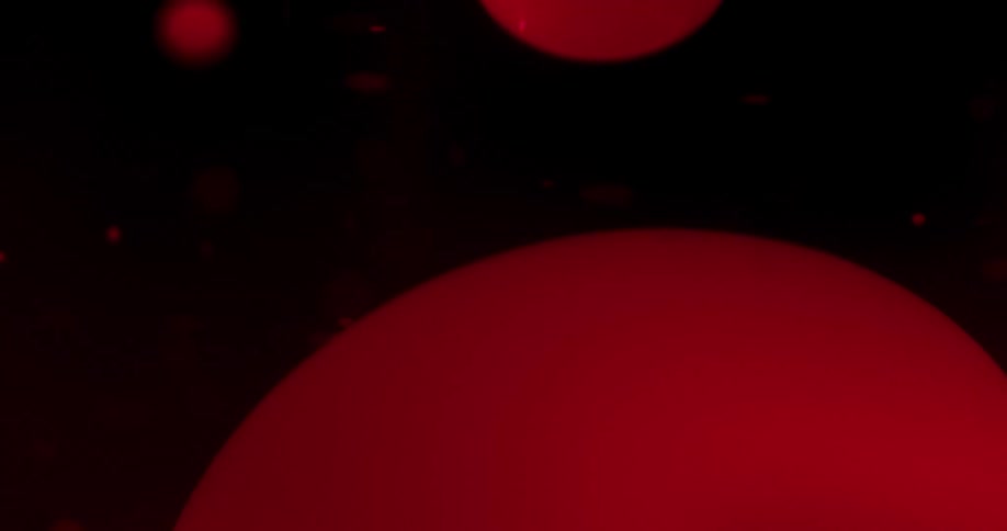 Red globs float and move against dark background