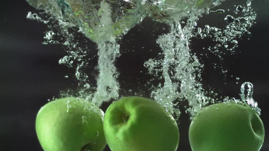Three green apples fall in the water