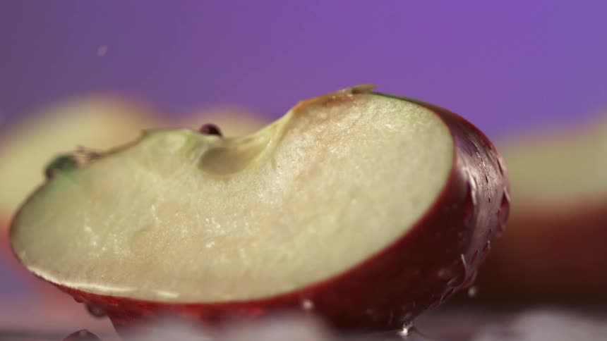 Water drips from a slice of red apple