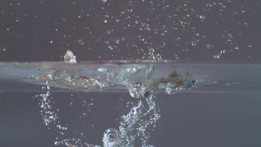 Two apples are dropped down in some water and make a big splash