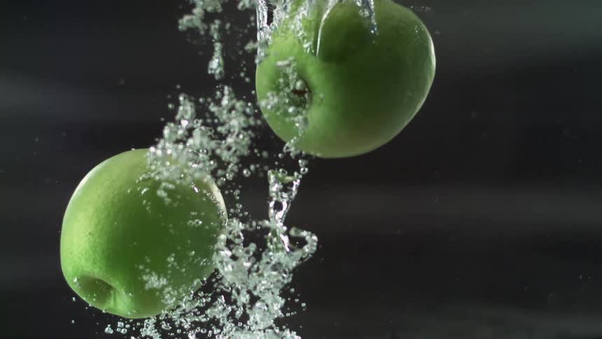 Fruit falling into water with bubbles with a black and gray background