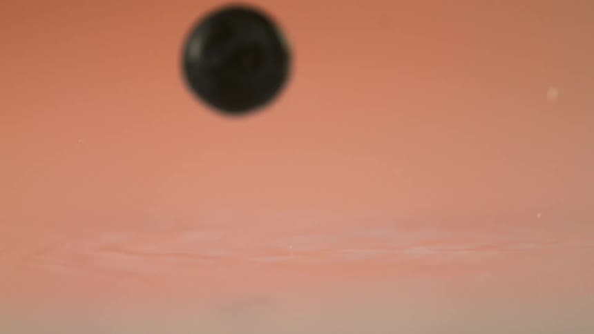 A piece of fruit drops down into water and splashes