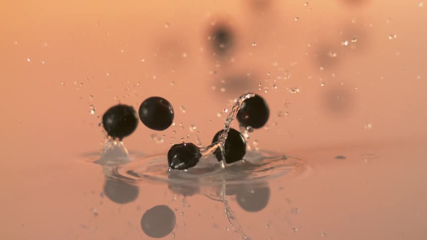 Fruits falling into shallow water with droplets