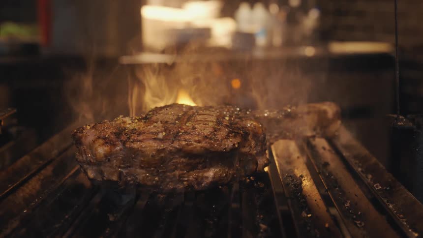 Steak is being smoked and grilled over coal fire