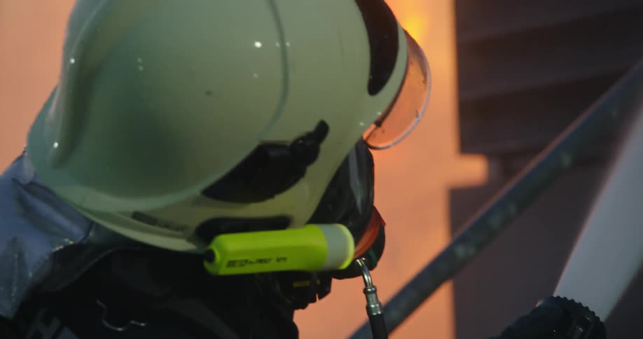 A firefighter holds a hose spraying water at a building fire
