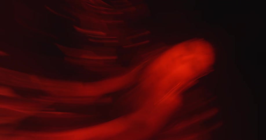 A woman in a red costume waves her arms around and drops to the floor in a dark room