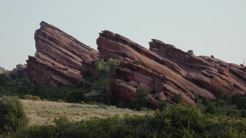 A large rock formation jutting out of a grassland during the day