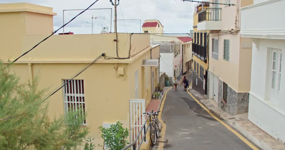 Two people walk down the middle of a road in a neighborhood