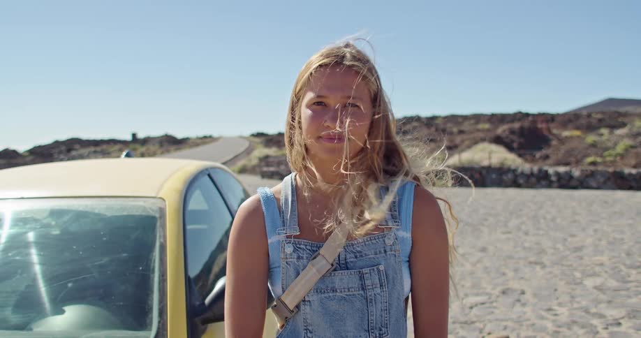 A woman is standing next to a car on the beach